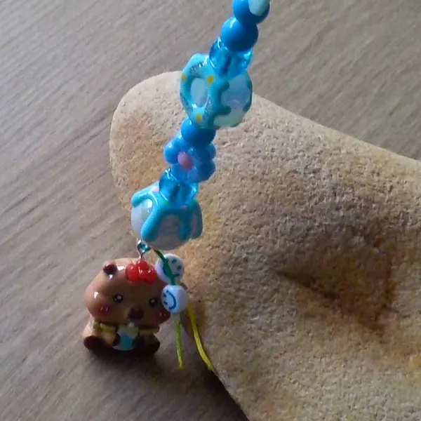 Bijou de telephone grigri de sac bébé capybara capibala mignon biberon perles acryliques donuts noeud papillon bleu fleurs